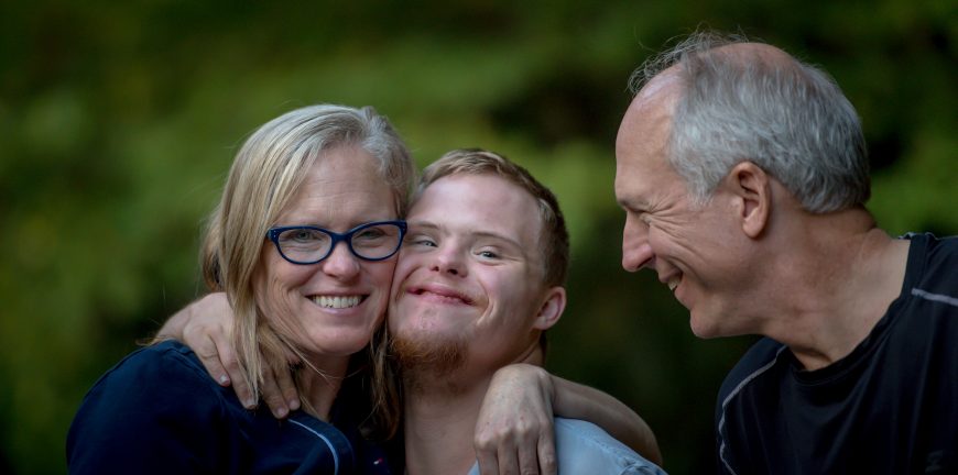 Mother, son, and father smiling and embracing